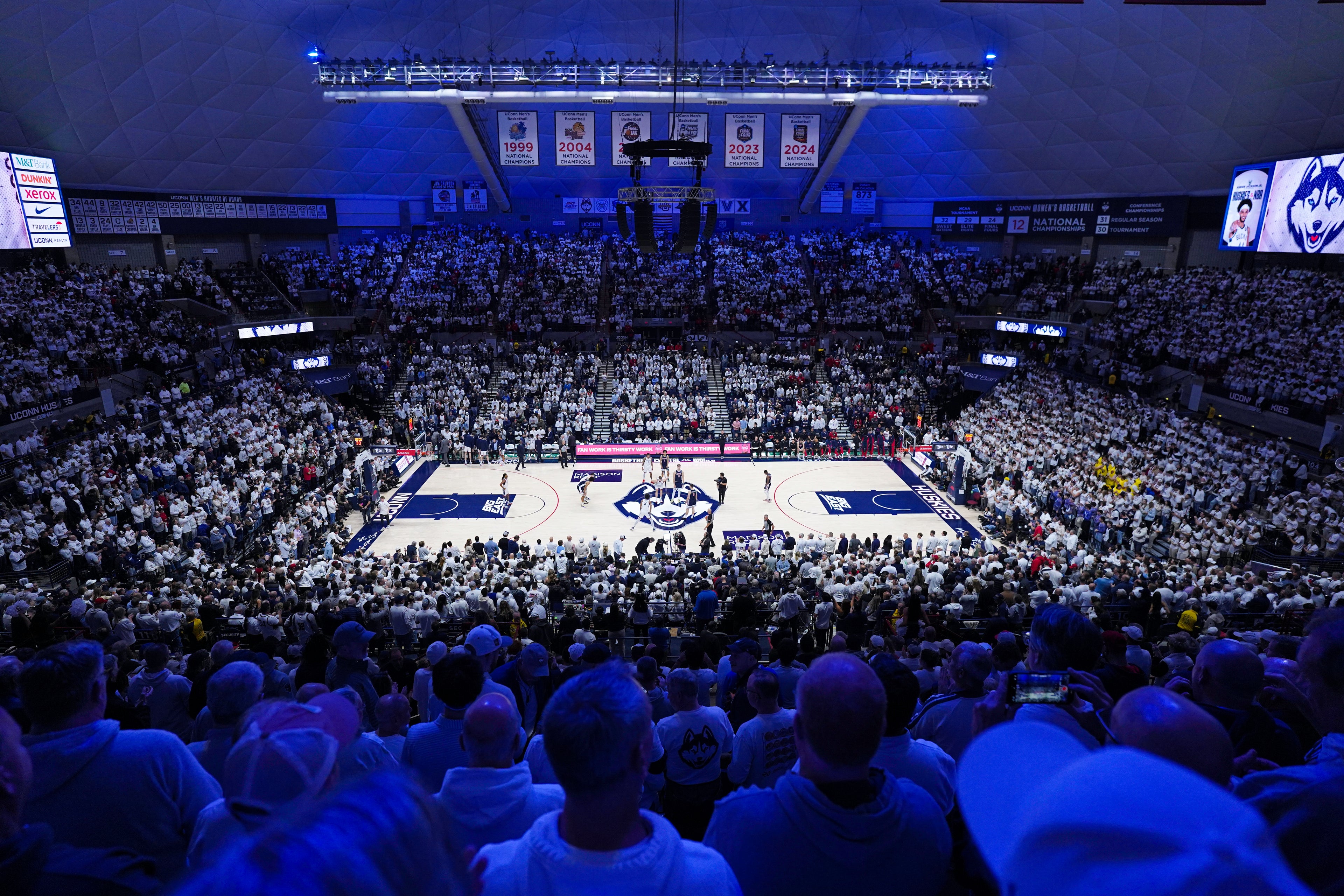 Basketball game in progress with a large crowd at UConn's Gampel Stadium.