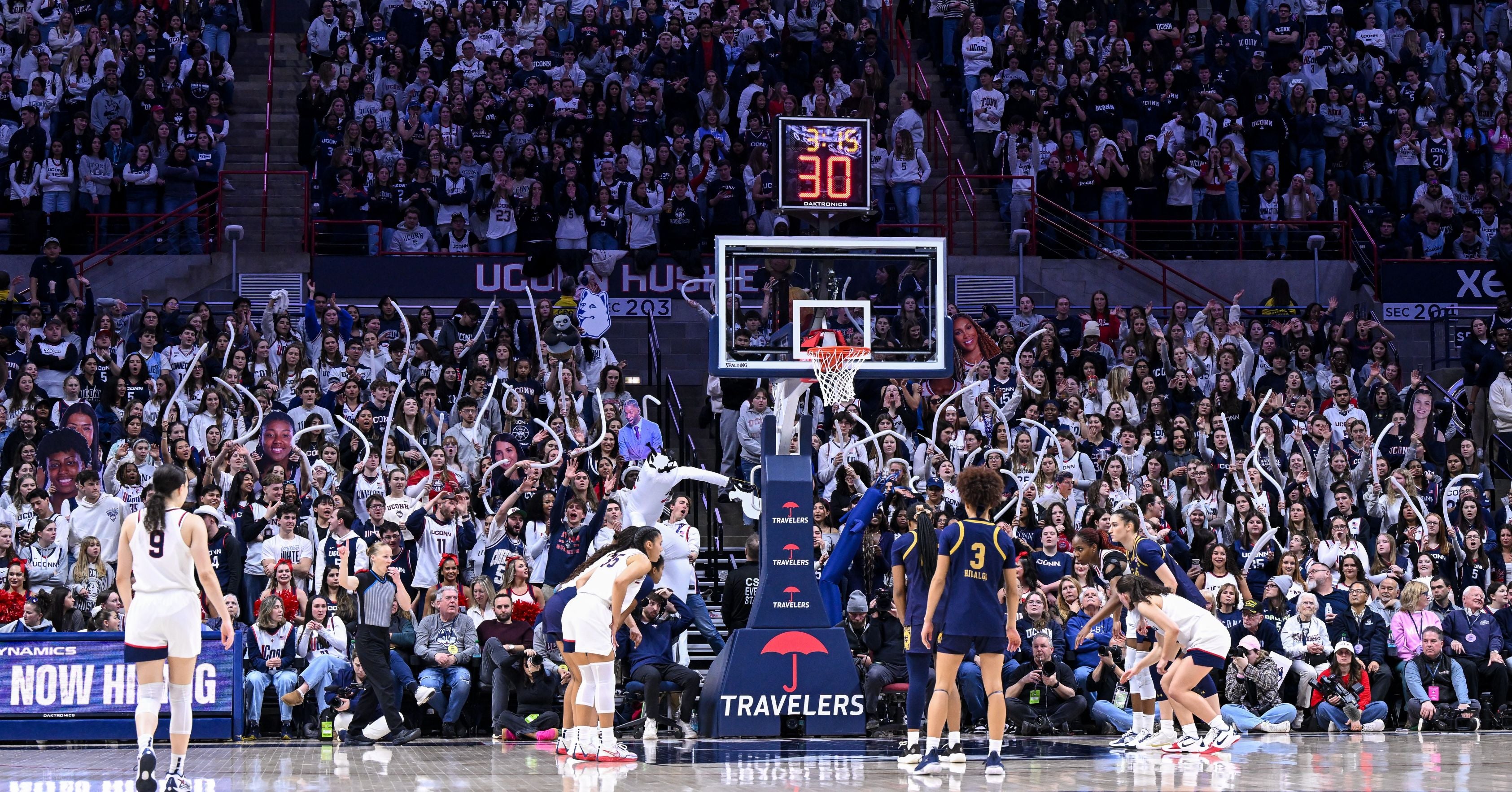 Basketball game in progress with players on the court and a crowd watching.
